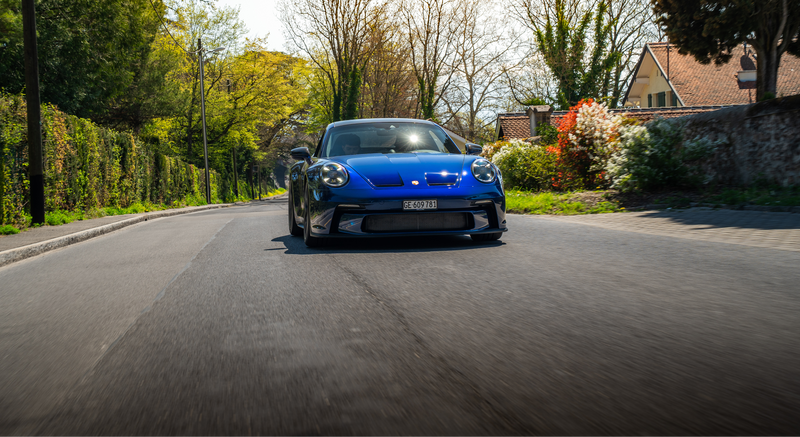 Blue sports car driving on scenic road inspired by automotive passion Trackerbs lifestyle image